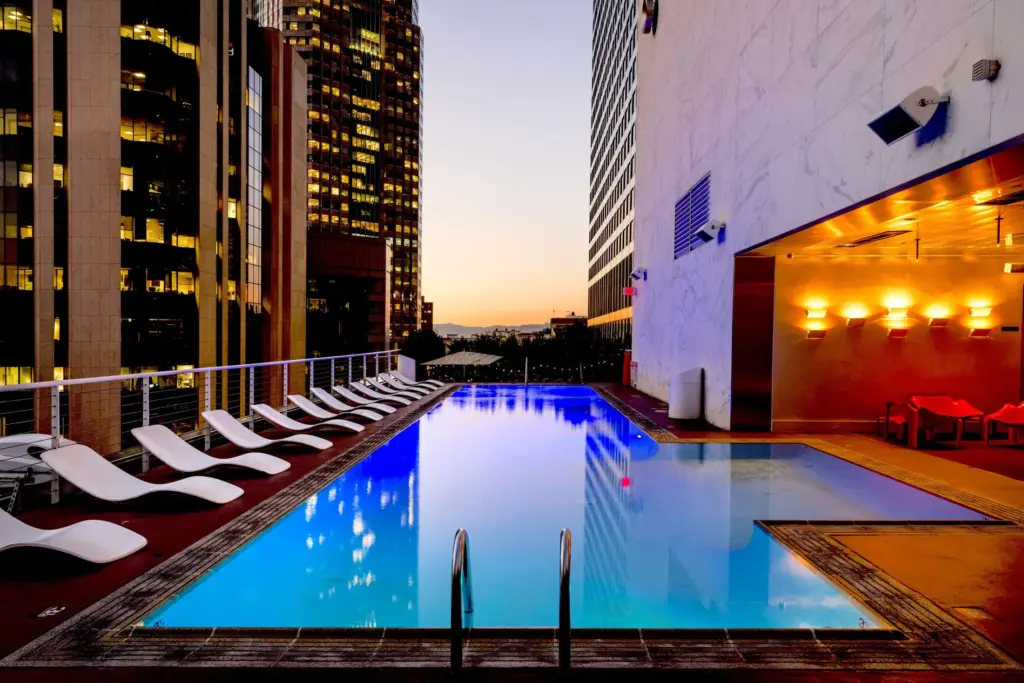 Rooftop hotel pool overlooking city towers at dusk